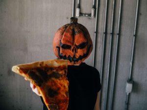 pumpkin head guy holding up a slice of pizza