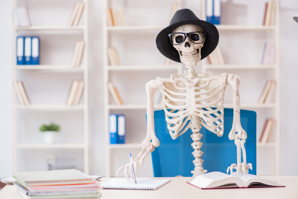 skeleton wearing a dress hat and glasses writing in notebook