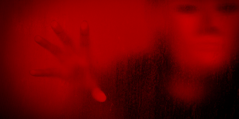 scary face and hand behind red window