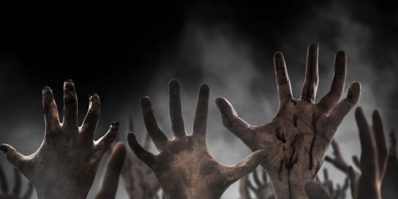 Zombie hands reaching out into the night foggy sky.