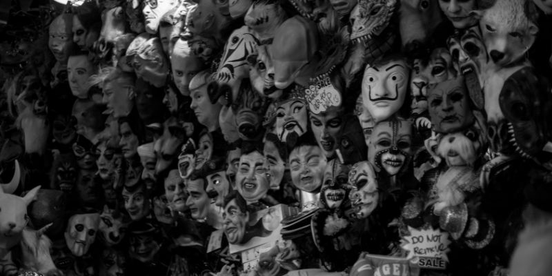 collection of creepy masks hanging on a wall