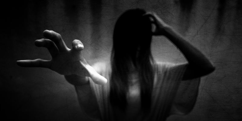 Black and white picture of a ghostly woman figure reaching her hand out.
