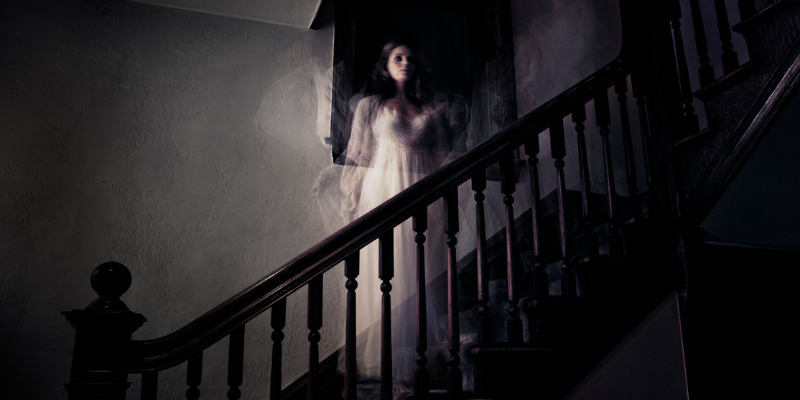 Ghostly woman figure standing on the stairs in darkness.