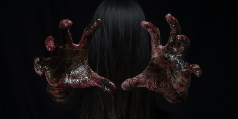 Two zombie hands covered in blood reaching out to the camera