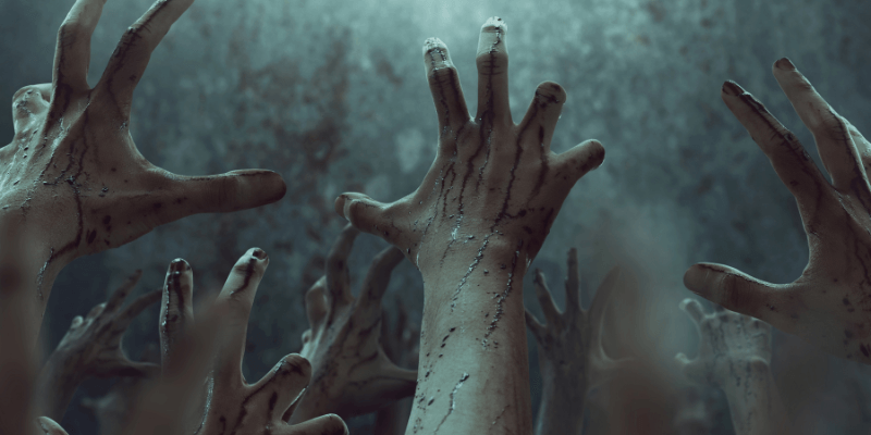 A group of bloody zombie hands reaching up into the air.

