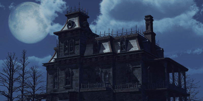 Exterior view of a haunted hotel with a full moon.