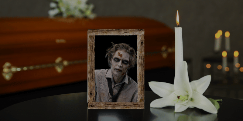 Framed photo of a zombie in front of a casket on a table next to a flower and candle.