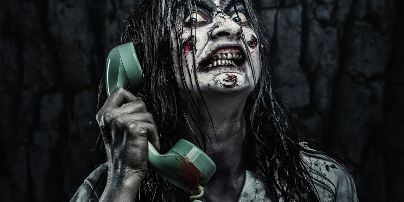 Portrait of a scary zombie girl calling by telephone