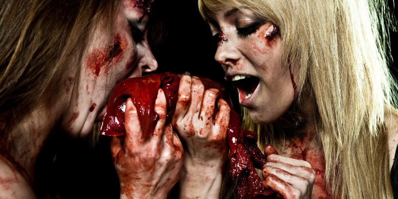 Young zombie_vampire girls closeup eating a bloody heart